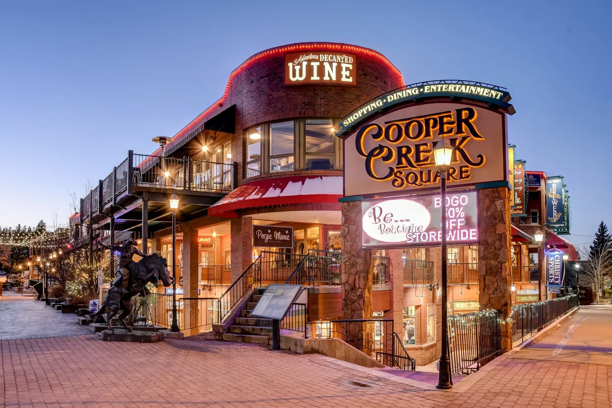 A lively scene at Cooper Creek Square, with decorative lighting and a welcoming wine store entrance. The area buzzes with activity, suggesting opportunities for gourmet dining, shopping, and entertainment just steps from the resort.