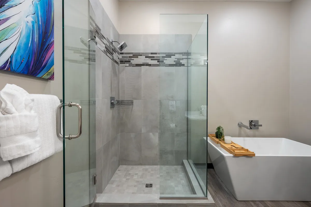 A luxurious bathroom featuring a glass shower enclosure, a freestanding bathtub, and colorful artwork. The space radiates tranquility and a spa-like ambiance, encouraging relaxation and rejuvenation.