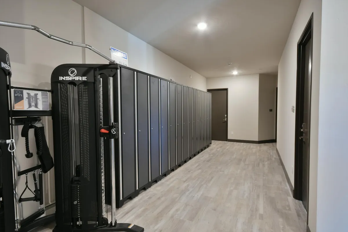 A modern fitness room equipped with various machines, lockers, and a motivating atmosphere. The space is clean and well-lit, providing a glimpse into the active amenities available regardless of the season.